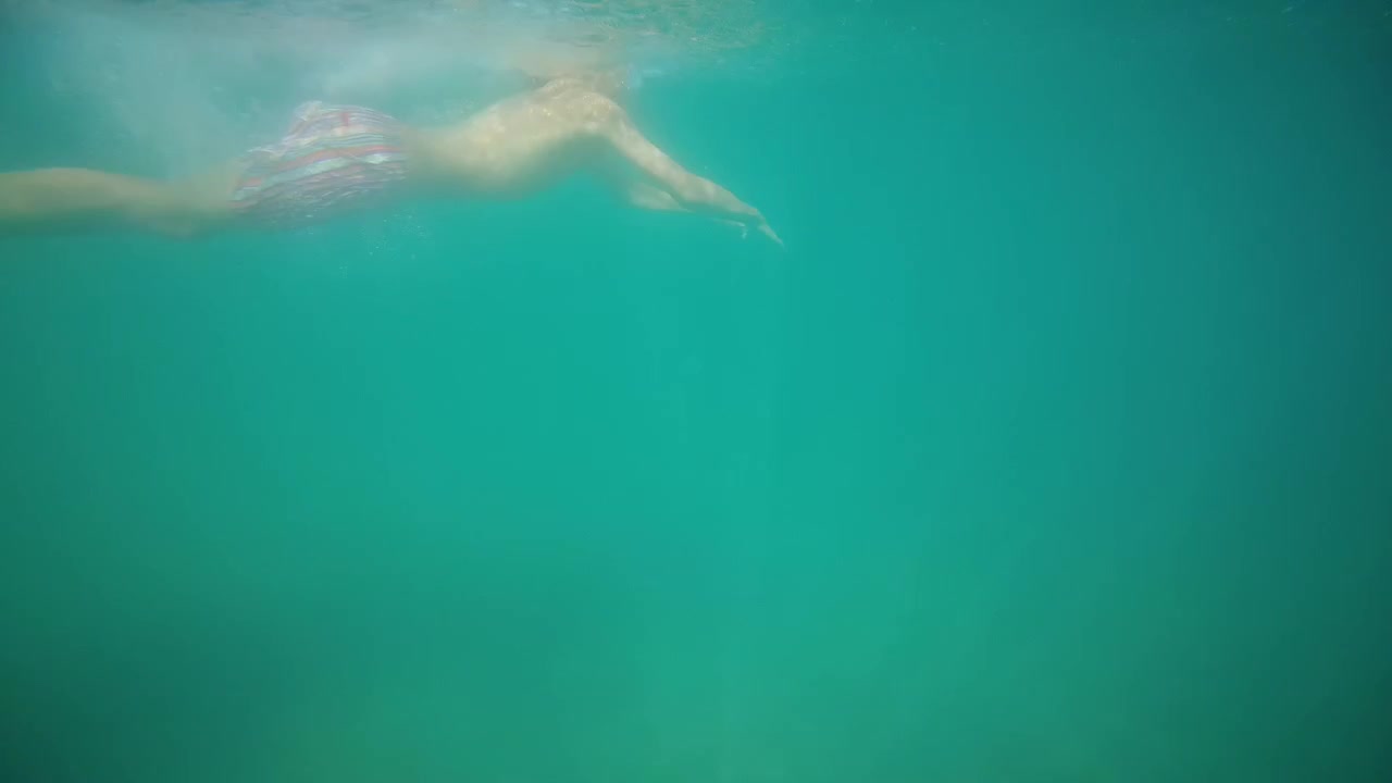 Persona nadando libremente en agua turquesa cristalina desde una perspectiva subacuática. Conceptos de libertad, verano, vacaciones y evasión.