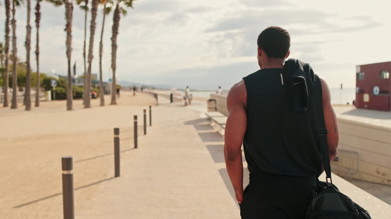 Fit Black Man Walks to the Beach for a Workout