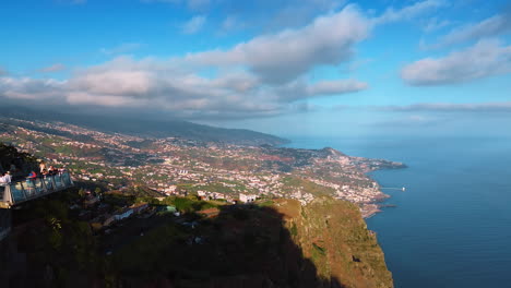 flying along the observation deck on the mountain with tourists on. splendid view of the highly-populated coast of madeira, portugal. aerial view.