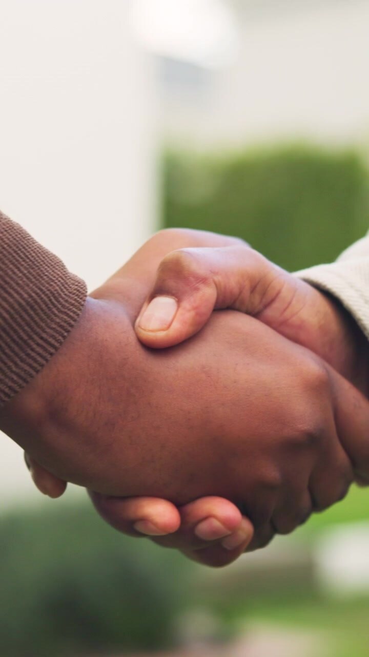 Two People Shaking Hands Outdoors