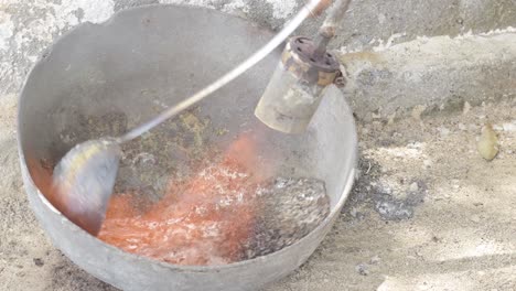 Old-fashioned-lead-casting-in-a-metal-bowl,-a-ladle-pouring-molten-lead,-traditional-craftsmanship