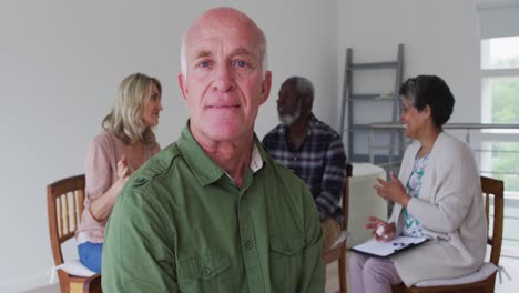 Two-diverse-senior-couples-sitting-in-circle-having-therapy-conversation-at-home-looking-at-camera