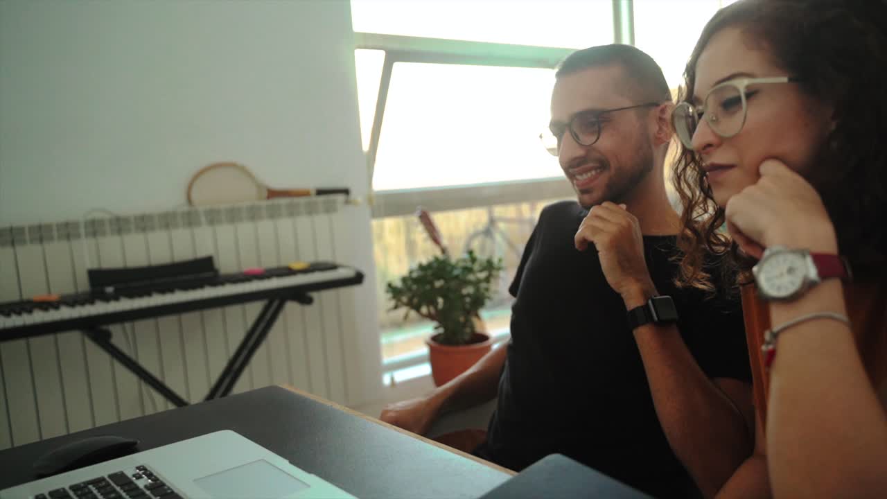 Happy couple having video conversation on laptop at home