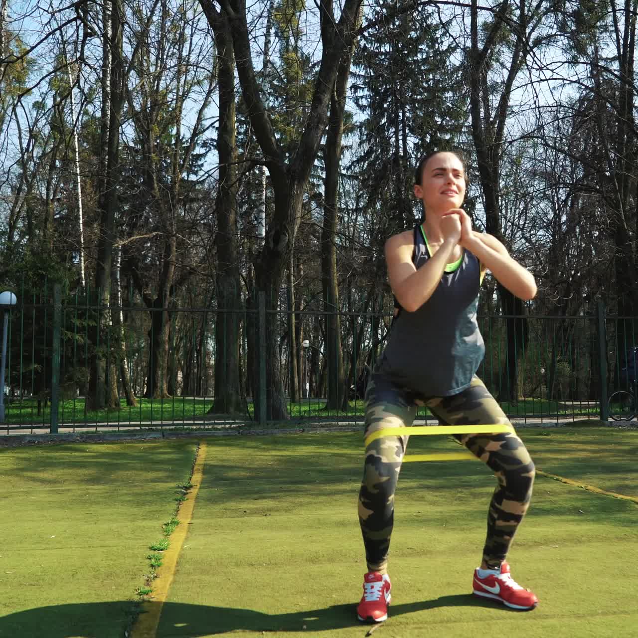 Woman doing exercises outdoors at the stadium. Beautiful young woman working with elastic band. Fitness concept.