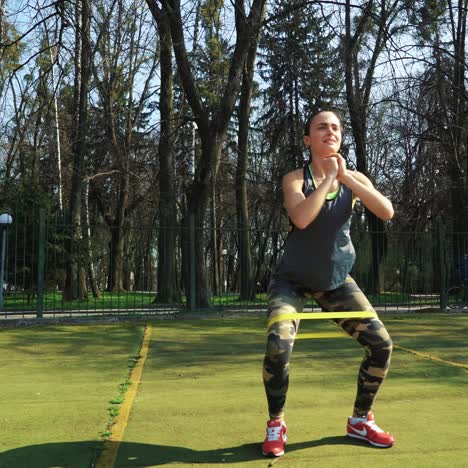 Woman doing exercises outdoors at the stadium. Beautiful young woman working with elastic band. Fitness concept.