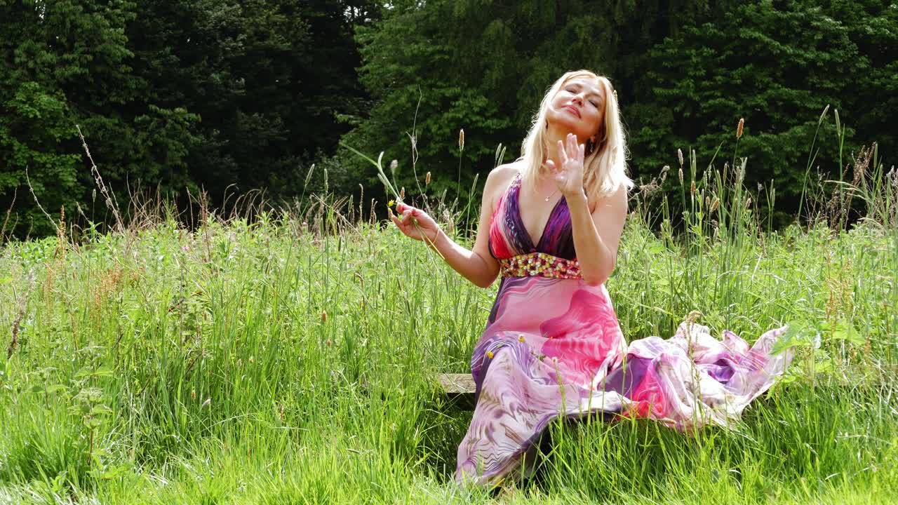 mujer atractiva saludando a la cámara en el fondo de la naturaleza verde ancho 4k disparo en cámara lenta