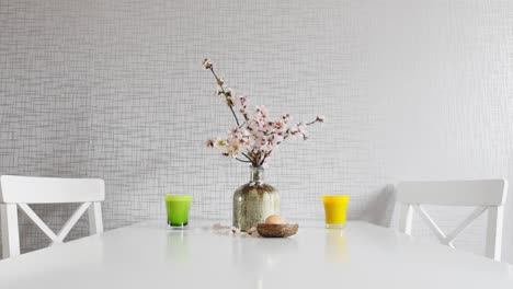 bright table with white chairs spring set up with coffee in cups; daisy flowers in vase.