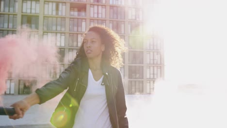 mujer joven de moda en el techo urbano usando una granada de humo