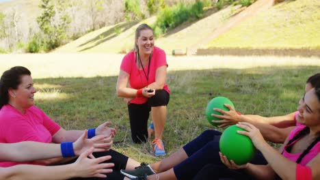 entrenadora que instruye a las mujeres mientras hacen ejercicio durante una carrera de obstáculos