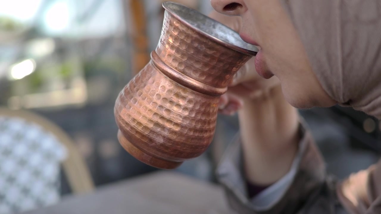 Kvinne som drikker kaffe fra tradisjonell kobberkopp