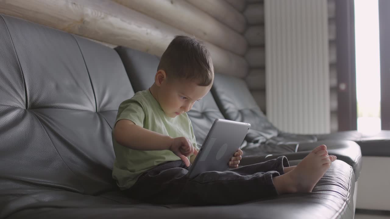 Modern child looking at the touchpad at home
