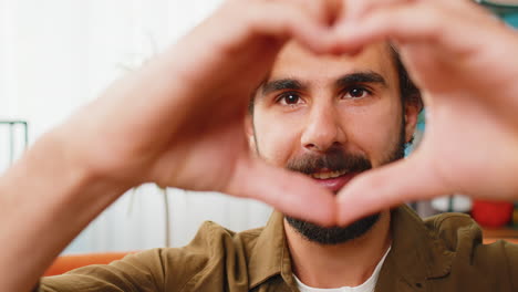 hombre árabe feliz hombre hace símbolo de amor mostrando el corazón señal a la cámara expresar sentimientos románticos