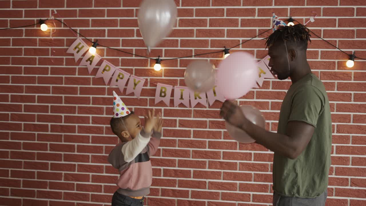 padre e hijo jugando a los globos en la fiesta de cumpleaños en casa