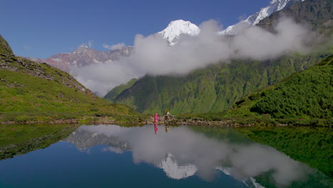 hipnotizante toma de drone refleja el lago, la vegetación el paisaje nepalí y la chica con un sari rosado disfruta de la naturaleza 4k