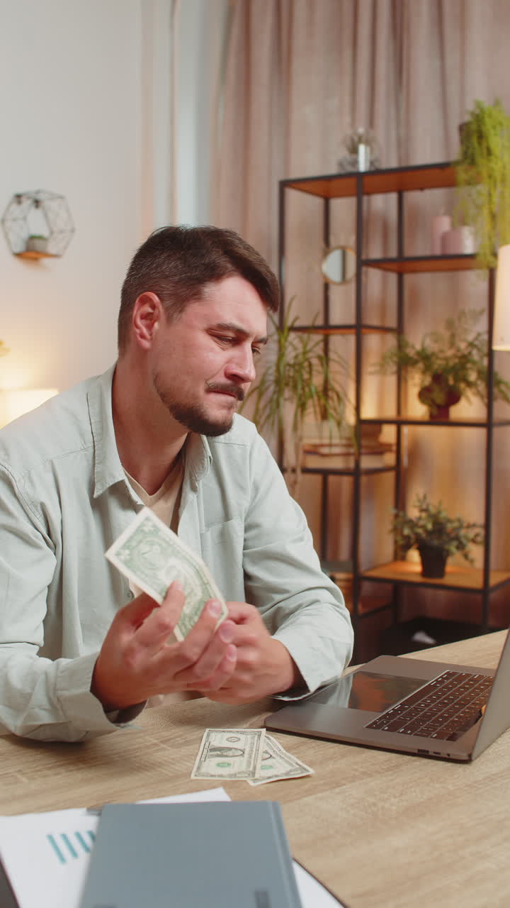 Upset caucasian man freelancer counting dollar cash insufficient amount of money sitting at table