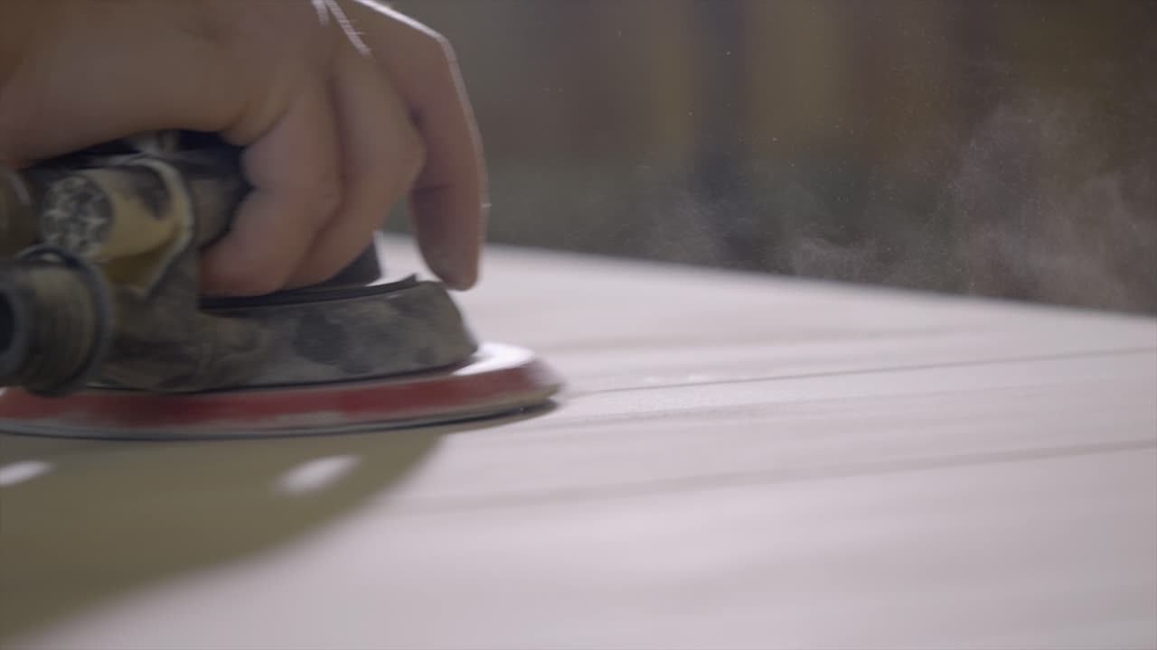 木工は,近距離で木材を滑らかにするために,空気圧軌道手の磨き砂機を使用します.