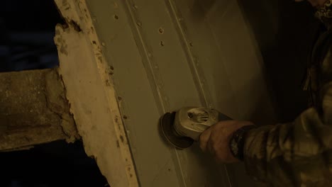 el carpintero quita las cabezas de los remaches de cobre que aseguran las costillas con una amoladora angular en un barco de madera interior