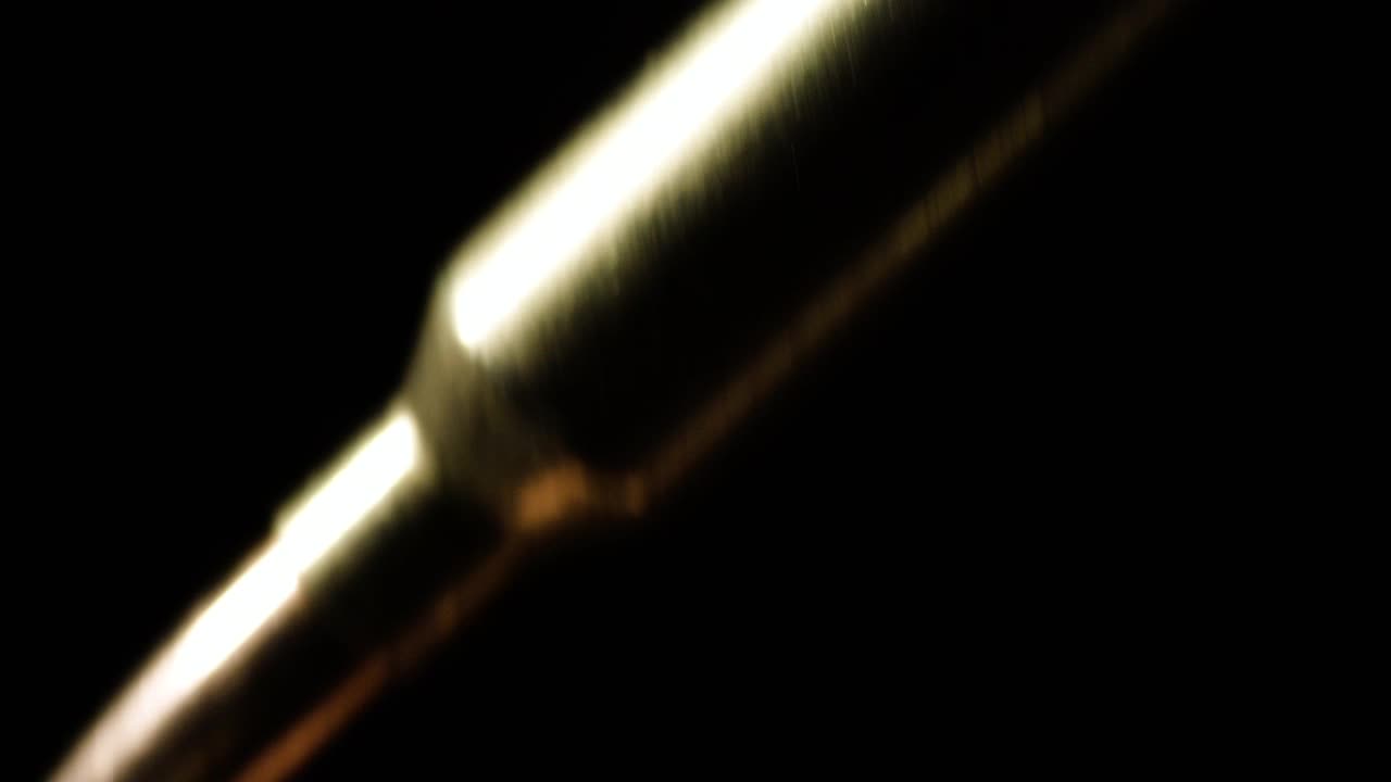 Close-up of 6mm ARC bullets falling in slow motion before a dark background