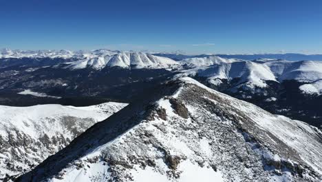 vista aérea, persona en el pico de la montaña y rango cubierto de nieve en el soleado día de invierno