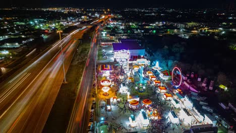 Hiperlapso-De-Drones-De-Carnaval-En-La-Ciudad-Por-La-Noche-Mientras-La-Gente-Acude-En-Masa-A-La-Rueda-De-La-Fortuna-Y-Otros-Juegos-Y-Atracciones-Alrededor-Del-Parque