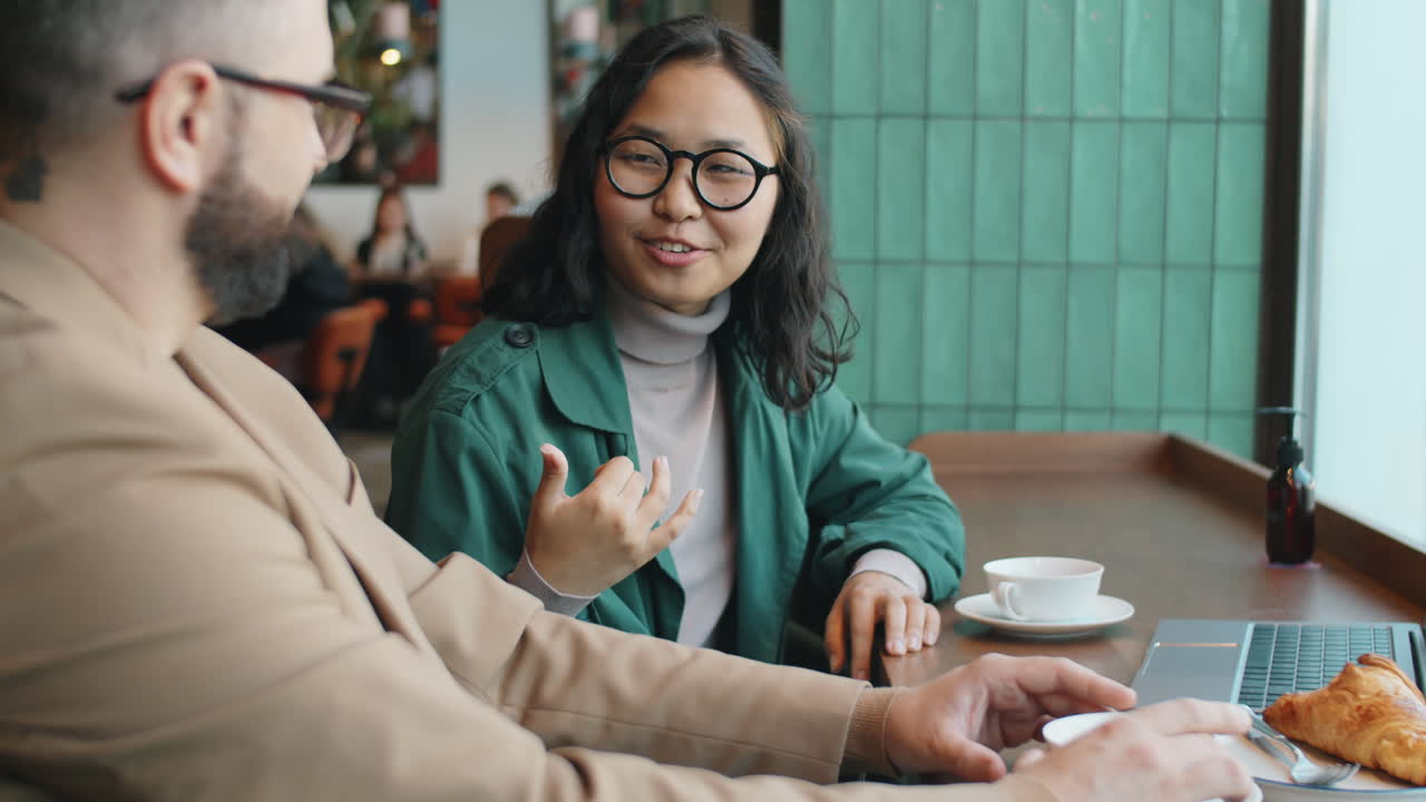 mujer de negocios asiática hablando con un compañero de trabajo sobre el té en una cafetería