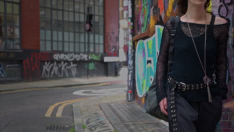 full length outdoor fashion portrait of young alternative style woman walking along london city uk street with graffiti covered walls in real time 2