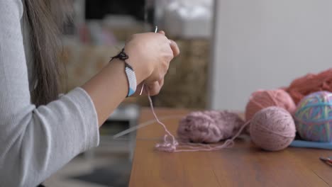 woman works on crocheting small round object that is delicate and intricate