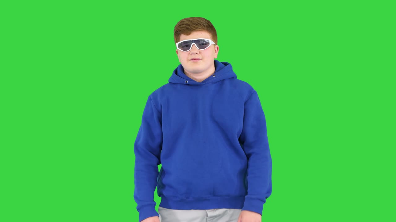 Teenager kid wearing casual clothes and sunglasses standing with arms crossed on a Green Screen, Chroma Key