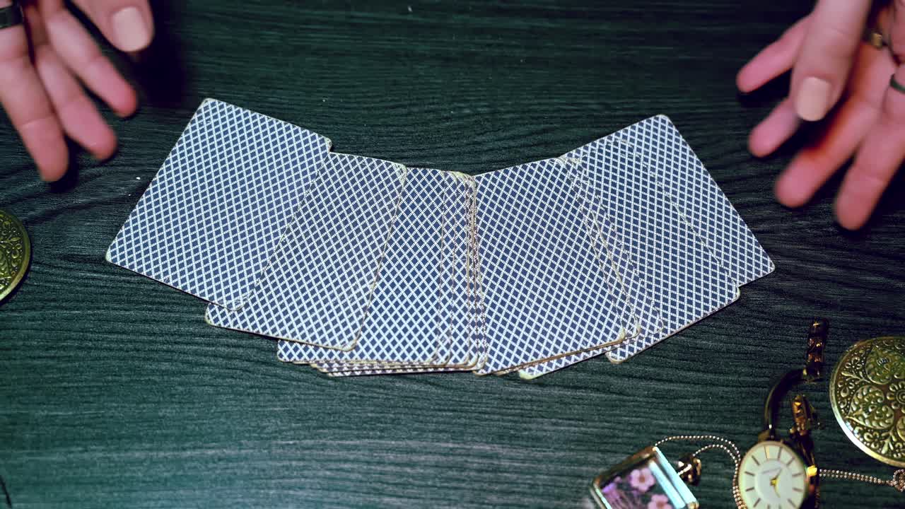 Fortune teller hands collects cards from the table among mysterious bright jewelry. Overhead shot