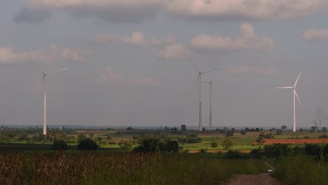 Wind Turbines Towering Farmlands, as farmers grow their crops and tend their animals; clean alternative energy in Thailand and mainland Southeast Asia.