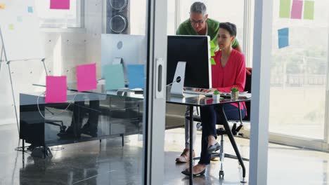 front view of caucasian business people discussing over computer at desk in office 4k