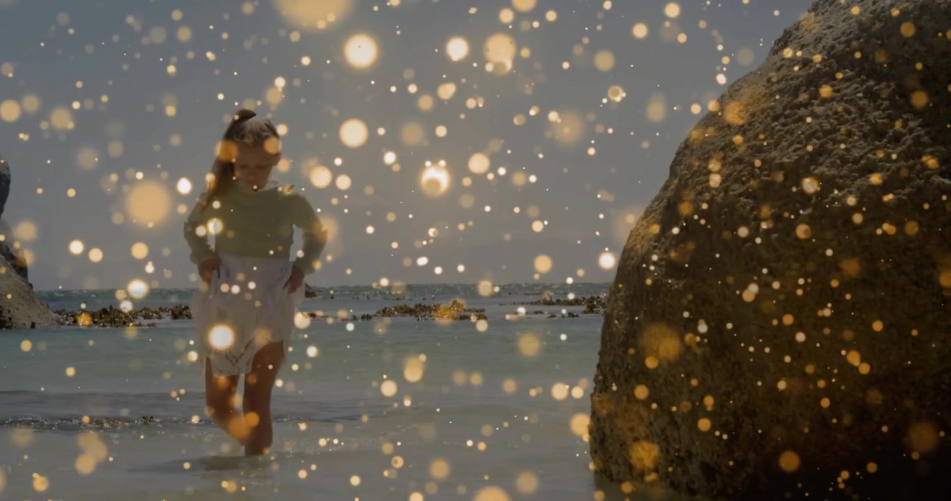 Vertikales Video: Mädchen watet knietief nahe einem Felsbrocken, goldenes Bokeh schwebt über dem Mädchen, für Natur.