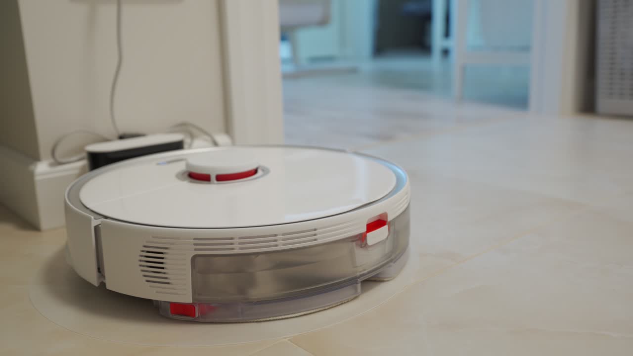 Smart robot white vacuum cleaner on charging station, automatic cleaning of apartment, modern technology of smart cleaning.