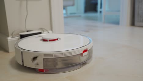 smart robot white vacuum cleaner on charging station, automatic cleaning of apartment, modern technology of smart cleaning.
