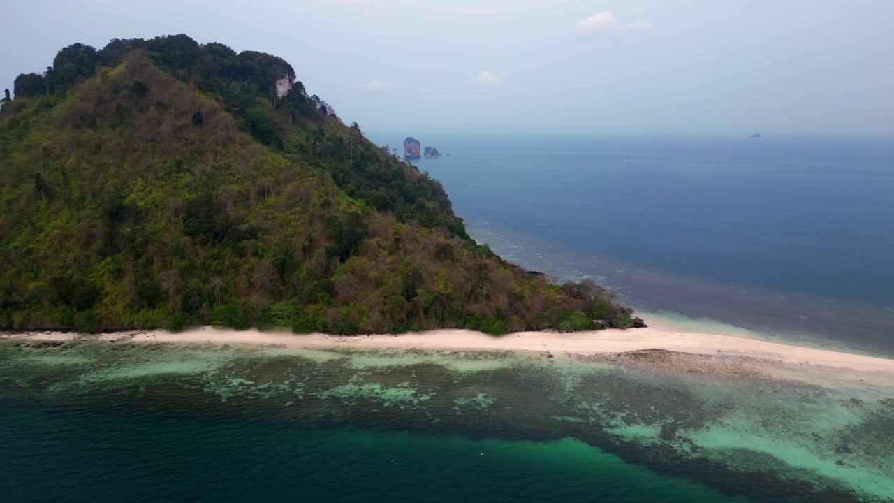 Railay Beach, Krabi, Thailand, featuring the iconic chicken head rock and lush tropical jungle meeting the turquoise Andaman sea. Unique aerial view flight