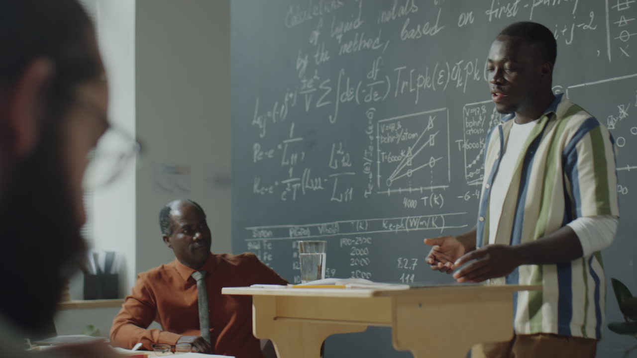Man giving a scientific presentation in front of a chalkboard