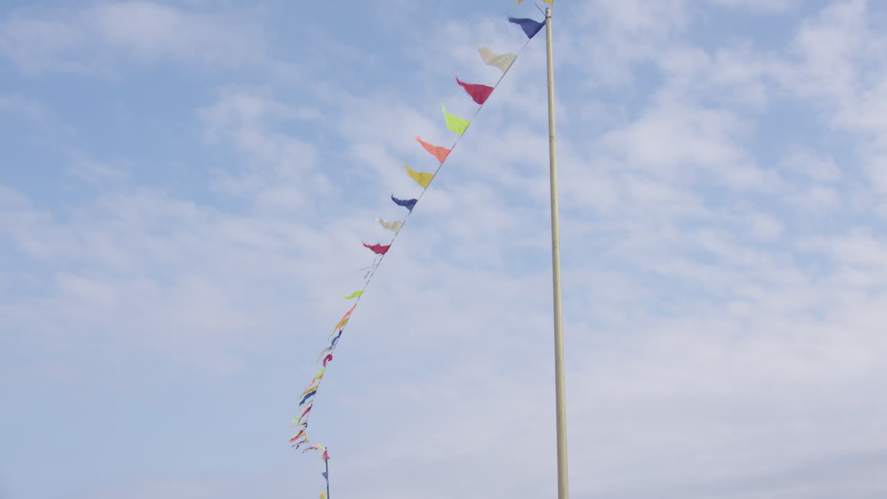 푸른 구름 배경에 다채로운 헌팅 플래그가 바람에 흩날리는 넓은 샷