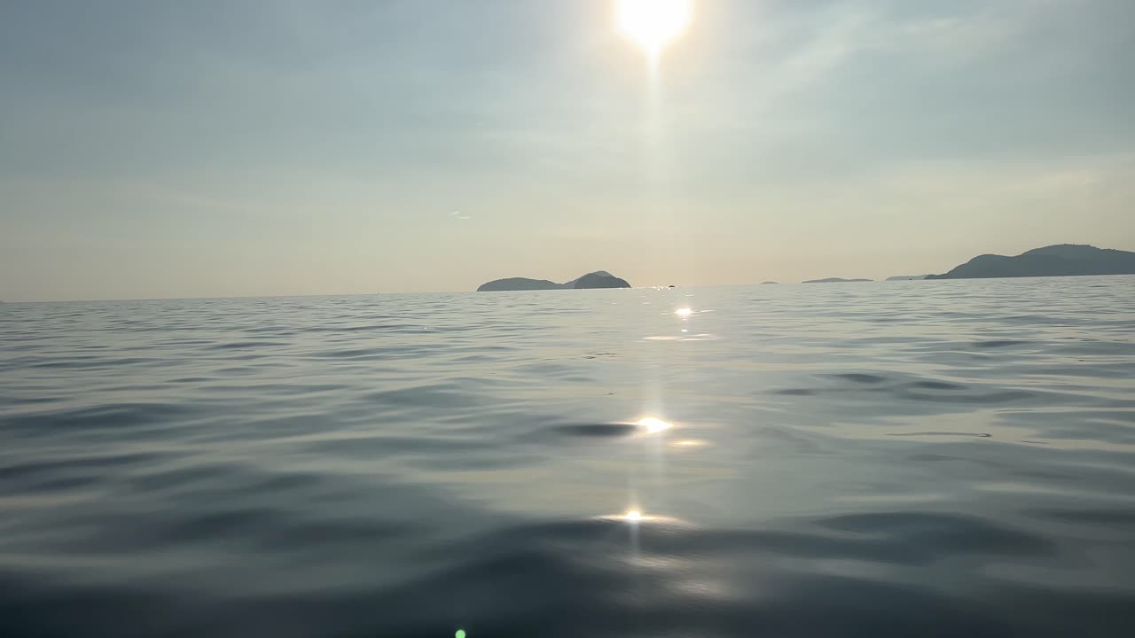 太陽がさざ波立つ水面にまばゆく反射する、タイの穏やかな開けたアンダマン海。
