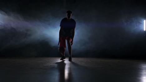 one-young-adult-man,-basketball-player-dribble-ball,-dark-indoors-basketball-court-slow-motion