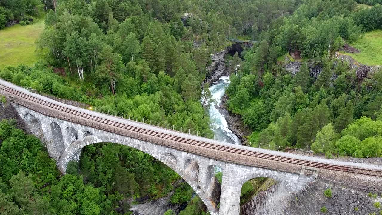 울창한 숲과 산으로 둘러싸인 킬링 브릿지의 항공 영상으로 건축적인 아름다움과 경치가 아름다운 주변을 보여줍니다.