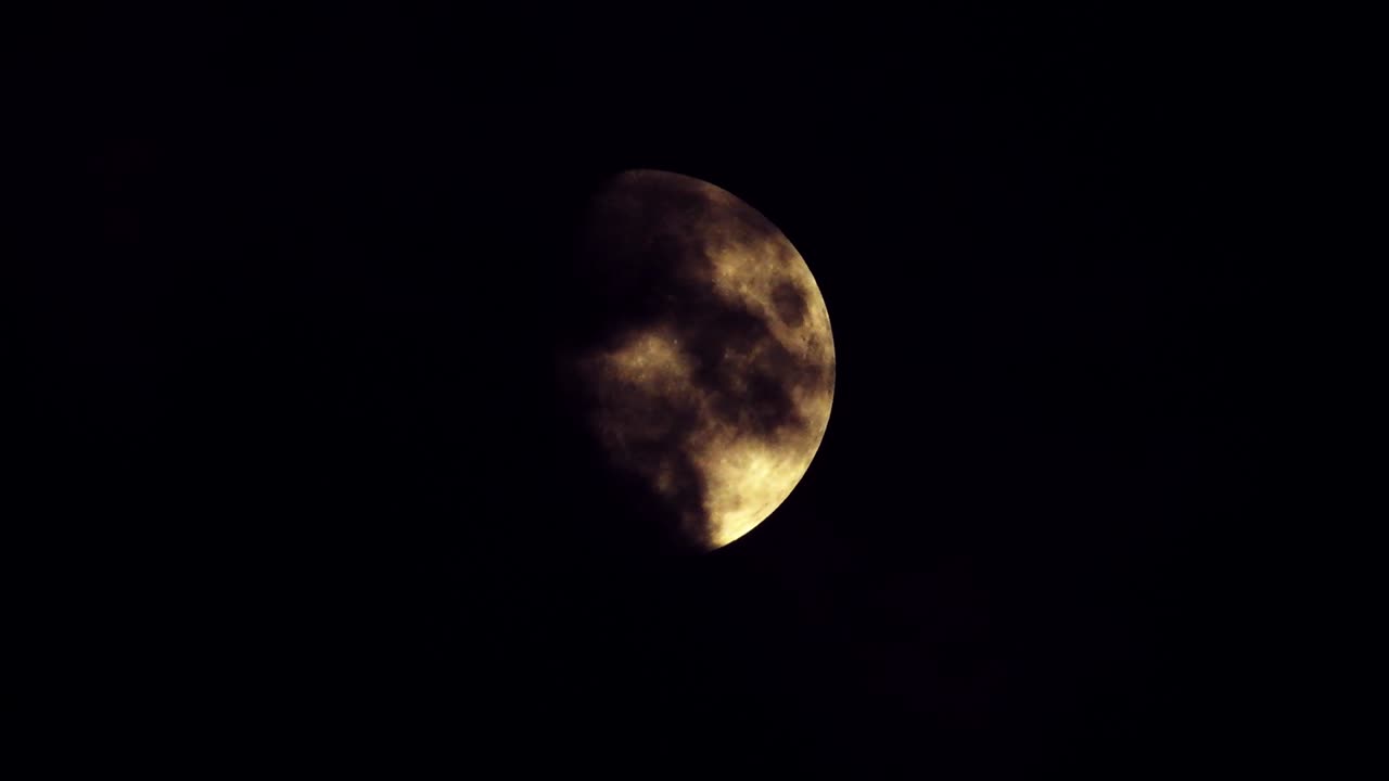Moon at night with cloud real time. 4k video moon in the black sky.  Clouds passing by moon at night. night sky with cloudy weather
