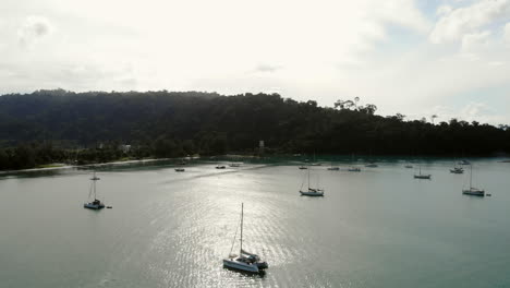 Aerial-Ascending-View-Of-A-Bay-With-Turquoise-Water,-Yachts-And-A-Lighthouse