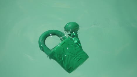 regadera de plástico verde flotando en la superficie de la piscina