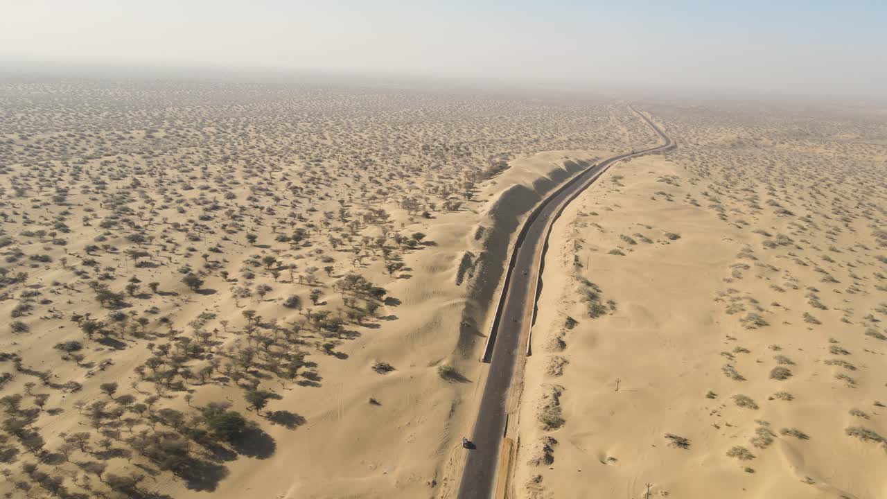 Aerial drone shot showcasing a bike journey through the barren and vast desert plains of Rajasthan.