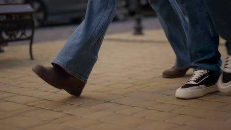 couple legs walking city street bouncing closeup. joyful friends going sidewalk