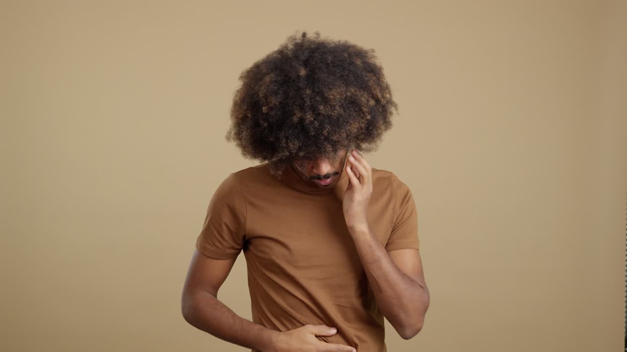 A man with an afro suffering from a headache or stress, holding his head in discomfort.