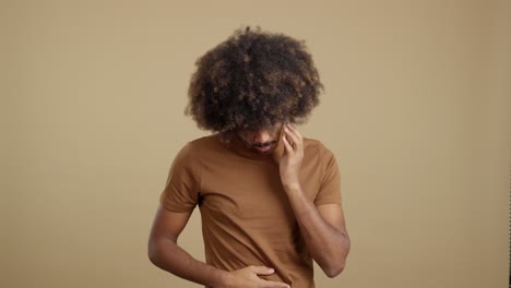 a man with an afro suffering from a headache or stress, holding his head in discomfort.