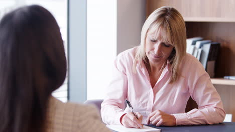 Businesswoman-Interviewing-Female-Candidate-At-Graduate-Recruitment-Assessment-Day-In-Office