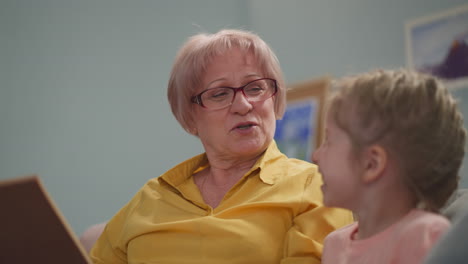 granny reads fairy tale to happy little child in living room