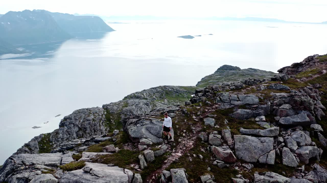 vista aérea de un hombre caminando en el pico de la colina de salberget en flakstadvag, noruega